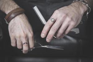retrato das mãos de um barbeiro segurando uma navalha e uma tesoura foto
