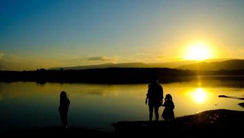 silhuetas de mãe e filho no lago na hora do pôr do sol, reservatório amphoe wang saphung loei tailândia foto