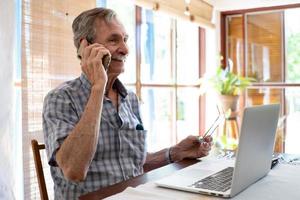 fechar sorrindo empresário falando com o telefone enquanto olha para o laptop foto