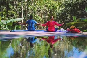 mulher asiática e homem asiático viajam pela natureza. viajar relaxar. conceito de postura de ioga, bons cuidados de saúde com posturas de ioga. exercícios ao ar livre relaxam a ioga. foto