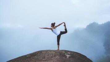 jovem exerce ioga nas montanhas. mulher asiática viajar natureza. viajar relaxar exercícios ioga tocar nevoeiro natural no pico da montanha. foto