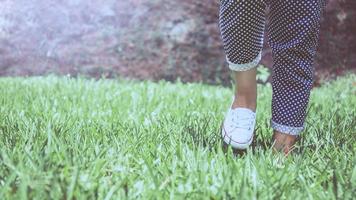 pernas de mulheres caminhando sobre um prado verde. foto