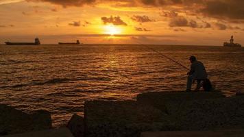 pescador ao nascer do sol na costa foto