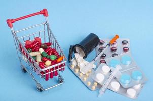 compre remédios. cesta de compras com vários medicamentos, pílulas, comprimidos sobre fundo azul foto