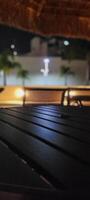 imagem do Sombrio mesa dentro jardim com piscina às noite foto