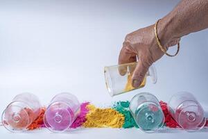 indiano mulher mãos derramando amarelo colori holi pó para dentro vidro frascos. foto