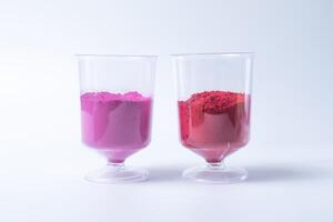 Rosa e vermelho holi pó areia dentro medindo copo isolado em branco fundo. foto