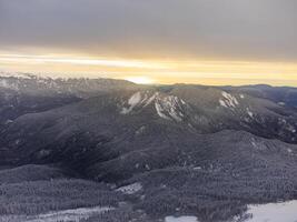 Visão do a inverno pôr do sol e coberto de neve montanhas dentro sochi foto