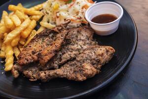 Preto Pimenta marinado frango filé com batata Gravetos em uma Preto prato foto