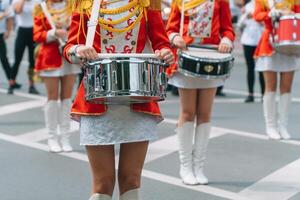 rua desempenho do festivo marcha do bateristas meninas dentro vermelho fantasias em cidade rua. jovem meninas baterista dentro vermelho vintage uniforme às a parada foto