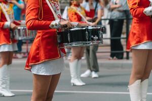 jovem meninas baterista dentro vermelho vintage uniforme às a parada. rua desempenho do festivo marcha do bateristas meninas dentro vermelho fantasias em cidade rua foto