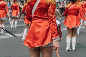 rua desempenho do festivo marcha do bateristas meninas dentro vermelho fantasias em cidade rua. jovem meninas baterista dentro vermelho vintage uniforme às a parada foto