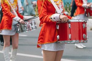 rua desempenho do festivo marcha do bateristas meninas dentro vermelho fantasias em cidade rua. jovem meninas baterista dentro vermelho vintage uniforme às a parada foto