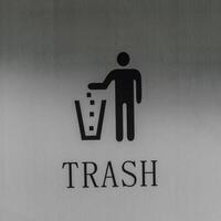 ícone do uma pessoa jogando Lixo para dentro uma Lixo pode em uma metal fundo. foto