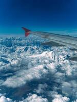 Visão do uma íngreme rochoso coberto de neve montanha alcance a partir de a avião janela foto