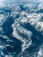 aéreo Visão do íngreme rochoso coberto de neve montanha alcance em lindo ensolarado dia foto