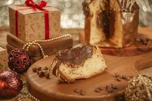 fatia de panetone de chocolate em uma tábua de madeira com enfeites de natal foto