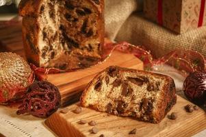 fatia de panetone de chocolate em uma tábua de madeira com enfeites de natal foto