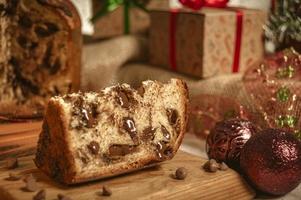 fatia de panetone de chocolate em uma tábua de madeira com enfeites de natal foto