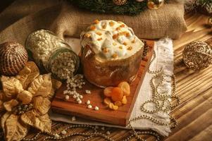 panetone de chocolate branco com damasco seco na mesa de madeira com enfeites de natal foto