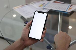 mão segurando Smartphone dentro escritório, usando telefone foto