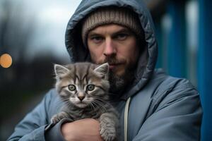 uma homem suavemente embalando uma pequeno gatinho dentro dele braços, mostrando Cuidado e afeição para a minúsculo felino. foto