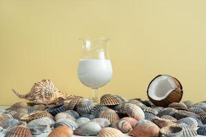 uma vidro do coco leite coquetel, uma coco e conchas do mar foto