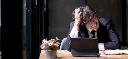 o triste empresário apertou a cabeça. um homem em estado de choque no fundo de um laptop. este homem recebeu más notícias. ruína do empresário. falência da empresa. problema. desespero. crise foto