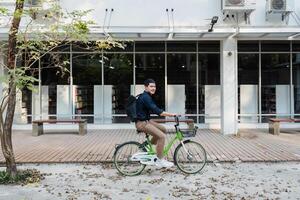 jovem homem de negocios passeio bicicleta para trabalhos para reduzir global aquecimento através a parque. eco amigáveis conceito foto
