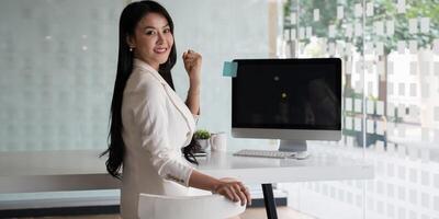 retrato do ásia empresária sorrir e sentado às dela escritório. foto
