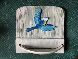 Novo caseiro pássaro alimentador, convexo silhueta desenhando do uma peito, porcelana placa, cinzento texturizado fundo foto