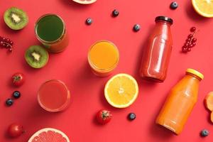 garrafas com suco saudável, frutas e vegetais na cor de fundo foto
