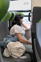 uma menina passeios uma trem sentado às a janela. a menina parece Infelizmente Fora do a janela, dizendo Tchau para dela parentes, ela folhas para outro cidade. foto