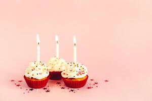 aniversário bolos de copo com creme de manteiga gelo e vela em Rosa pastel fundo. foto