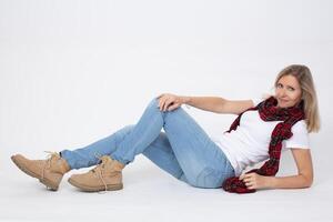 adulto lindo delgado mulher dentro jeans e chuteiras posando enquanto deitado dentro a estúdio. foto