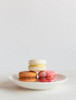 três francês macarons em uma branco placa. mínimo conceito, Lugar, colocar para texto. foto