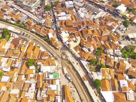 surpreendente panorama do trem faixas. pássaro olho Visão a partir de zangão do uma estrada de ferro linha dentro a meio do densamente populosa casas dentro cicalengka, Indonésia. tiro a partir de uma zangão vôo 200 metros alto. foto