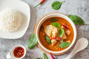 tradicional tailandês frango vermelho Curry com fresco vegetal e erva dentro tigela em mesa, tailandês Comida conceito com arroz foto