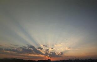 lindo nascer do sol com caloroso laranja luz solar e feixes através azul céu foto