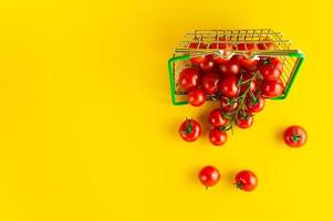 tomates cereja espalhados em uma cesta em um fundo amarelo brilhante com um lugar vazio para uma inscrição. foto