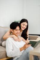 jovem casal ações uma sorrir Como elas saciar dentro a simples prazer do lendo uma livro junto. foto