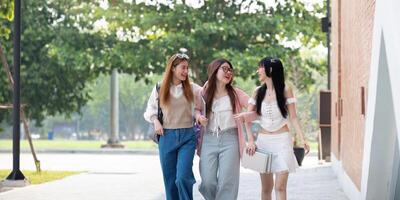 Faculdade amigos andar para classe junto. universidade aluna dentro campus conversa e ter Diversão ao ar livre foto