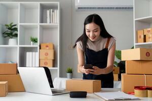 jovem mulheres levando foto produtos com célula Telefone ou Smartphone digital Câmera para postar para vender conectados em a Internet e preparando pacote produtos caixa. vendendo conectados Ideias conceito