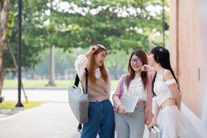 Faculdade amigos andar para classe junto. universidade aluna dentro campus conversa e ter Diversão ao ar livre foto