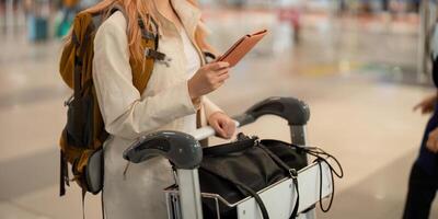 mão do mulher passageiro segurando Passaporte com a voar dentro aeroporto terminal foto