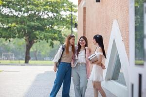 Faculdade amigos andar para classe junto. universidade aluna dentro campus conversa e ter Diversão ao ar livre foto