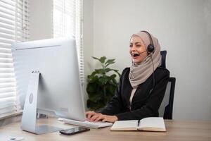 jovem muçulmano mulheres vestindo hijab telemarketing ou ligar Centro agente com fone de ouvido trabalhando em Apoio, suporte linha direta às escritório foto