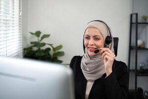 jovem muçulmano mulheres vestindo hijab telemarketing ou ligar Centro agente com fone de ouvido trabalhando em Apoio, suporte linha direta às escritório foto