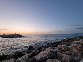 sem fim Visão do oceano com pedras em a pôr do sol foto