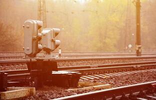 foto de um fragmento de uma ferrovia com um pequeno semáforo em tempo chuvoso